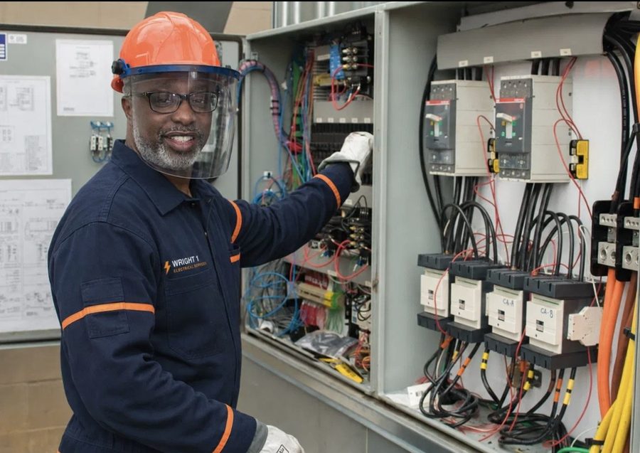 Clyde Wright in hard hat working on commercial equipment circuits